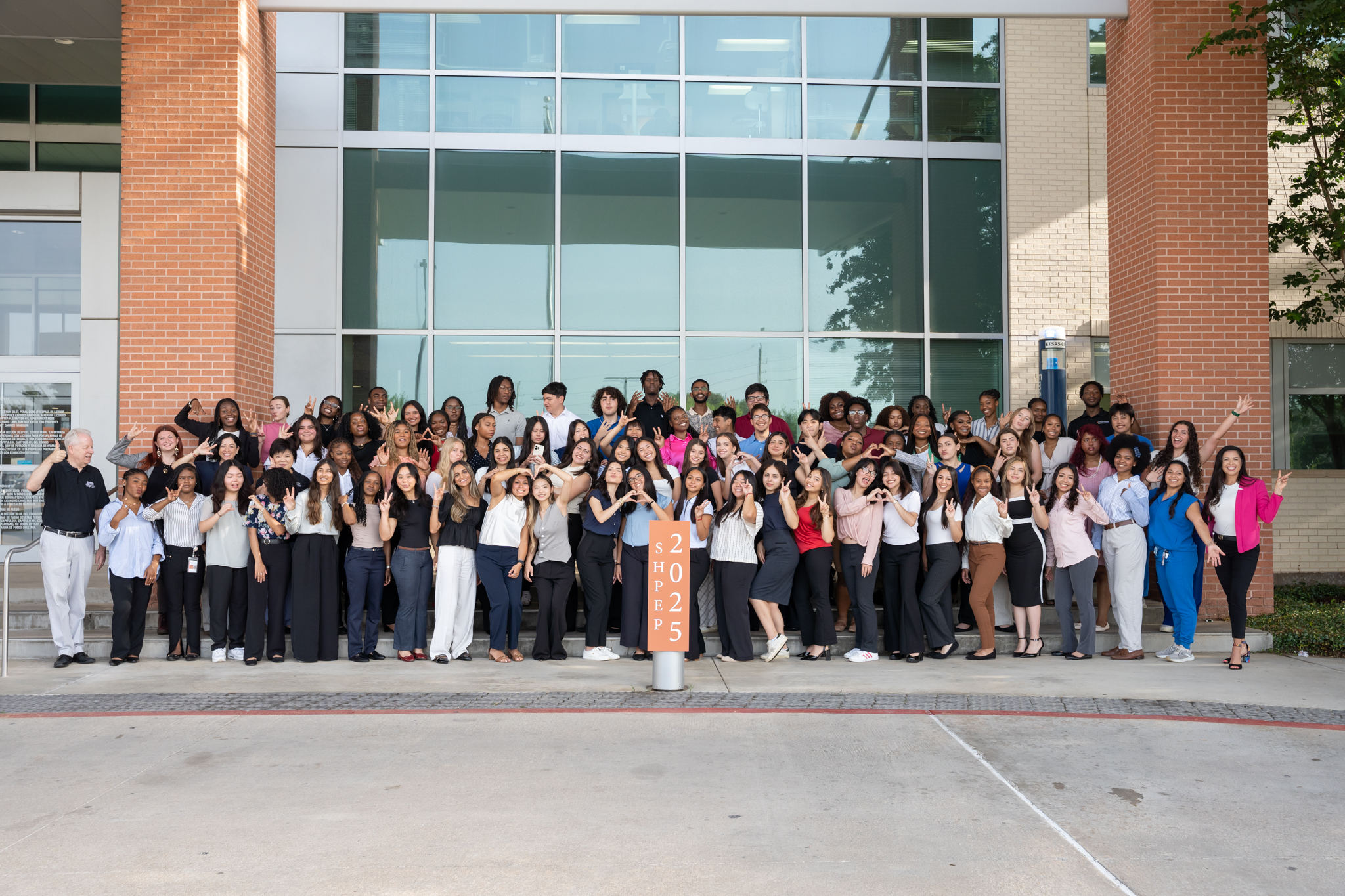 Large group of individuals standing together outside a building, posing for a group photo next to a SHPEP 2025 sign.